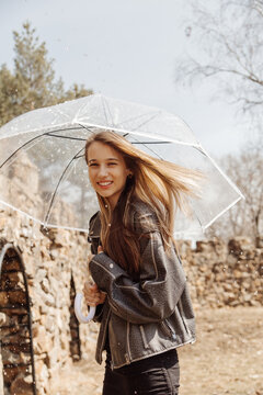 Smiling girl with transparent umbrella in autumn park