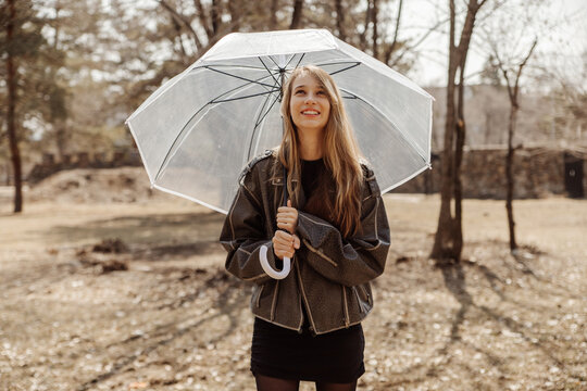 Smiling girl with transparent umbrella in autumn park