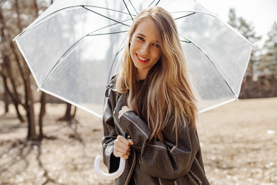 Smiling girl with transparent umbrella in autumn park