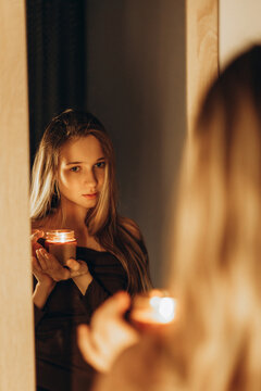 Girl holding scented candle before a mirror
