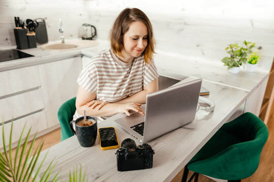 Woman photographer working remotely on laptop at home