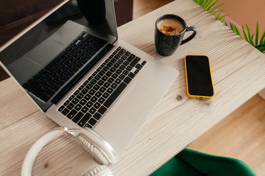 Laptop workspace with coffee, smartphone and headphones