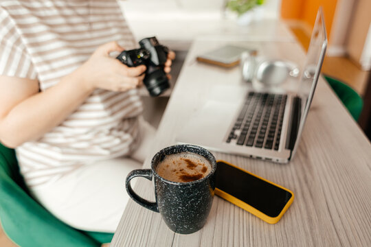 Woman photographer working remotely with laptop and camera