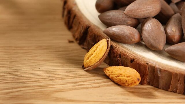 Chinese torreya nuts with cracked yellow kernels on a rustic wooden slice.
