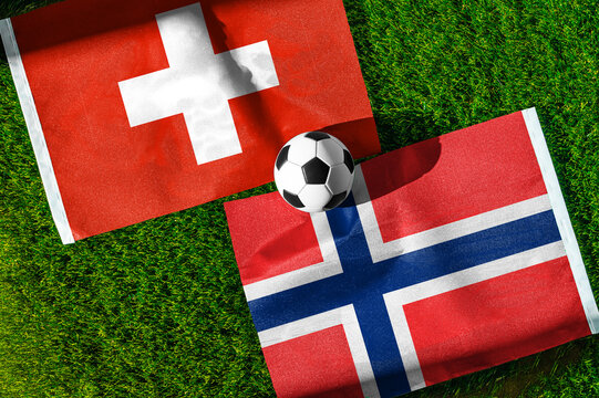 Switzerland vs. Norway football match. National flags on green grass with soccer ball in the middle. Football background for international match.