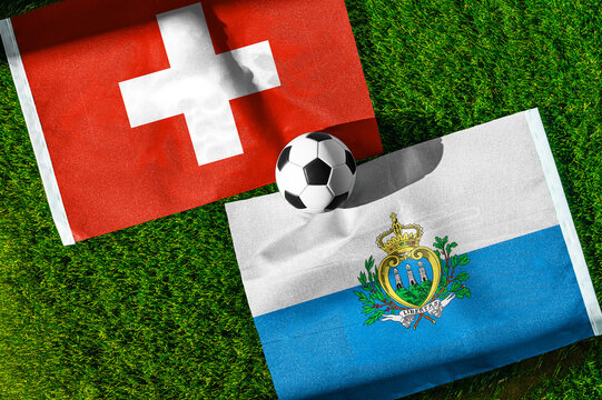 Switzerland vs. San Marino football match. National flags on green grass with soccer ball in the middle. Football background for international match.