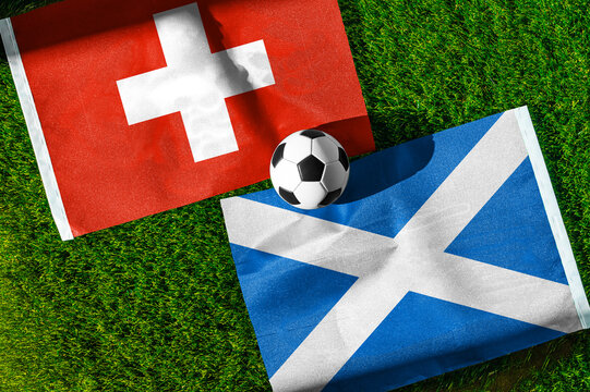 Switzerland vs. Scotland football match. National flags on green grass with soccer ball in the middle. Football background for international match.