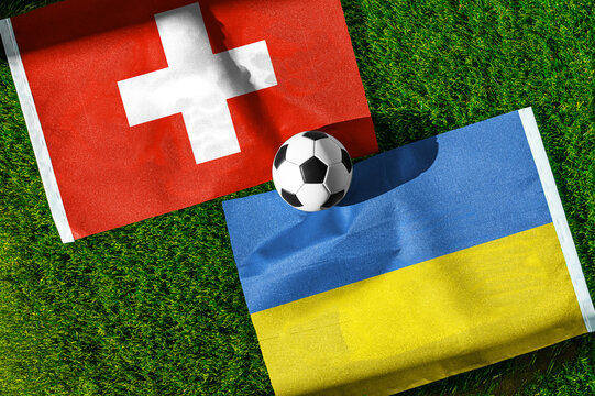 Switzerland vs. Ukraine football match. National flags on green grass with soccer ball in the middle. Football background for international match.