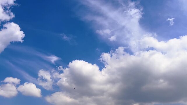 Large white clouds drift across a vivid blue summer sky