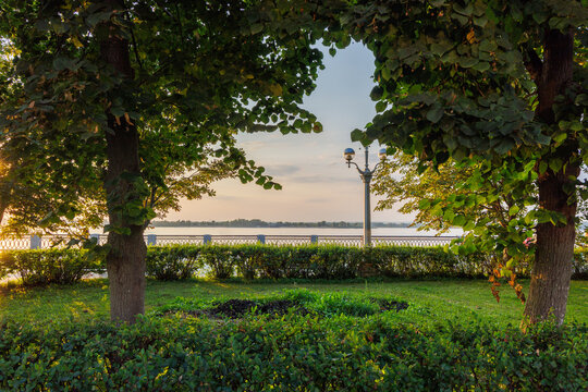 Green riverside park with trees and landscaped garden