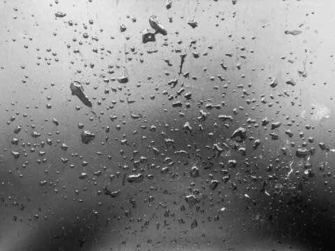 Rain condensation on cool grey surface creating abstract liquid texture for modern graphic backgrounds.