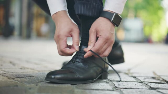 Close up of a businessman tying his leather shoelaces on a step