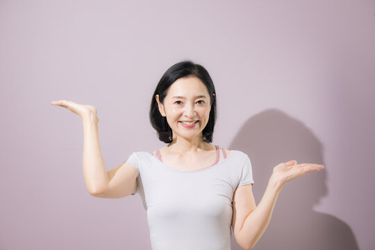 両手を広げて二つの選択肢を比較する日本人ミドル女性、スポーツ系の商品やサービスの違いを紹介する笑顔の女性