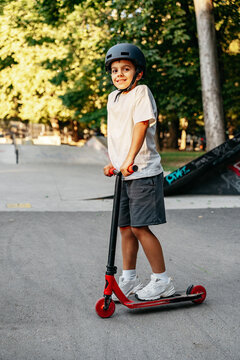 Boy riding a scooter in a park during daytime with trees in the background