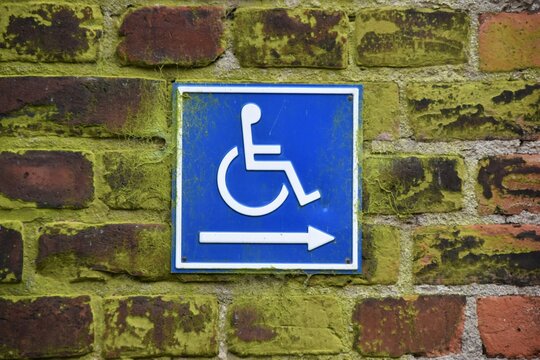 Blue sign on a brick wall with an arrow pointing