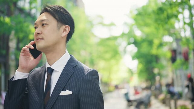 Japanese businessman talking on the phone and looking up at the sky