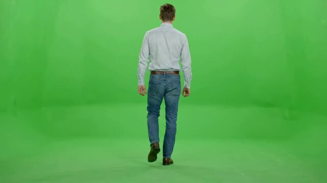 Man walking away in casual shirt and jeans on green screen background, for easy compositing, back view