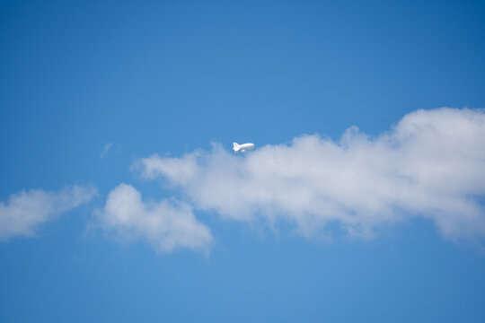 Tethered aerostat floating on blue sky with white clouds, helium surveillance balloon, high altitude monitoring airship