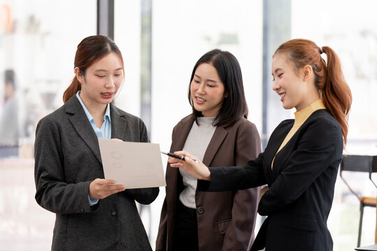 Asian Business Women Pointing at Document and Discussing Strategy