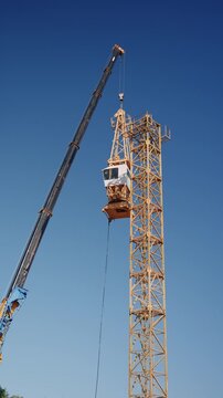 Large mobile crane lifting a tower crane section during construction of a new building