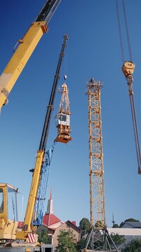 Large mobile crane lifting a tower crane section during construction of a new building