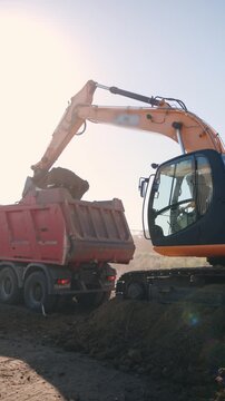 Excavator loading excavated soil into a heavy dump truck during earthmoving and foundation work.
