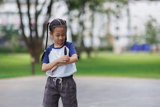 Young girl scratching itchy skin on arm outdoors