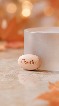 A fisetin supplement sits on a smooth stone surface next to autumn leaves. The background is warm with soft light creating a cozy atmosphere