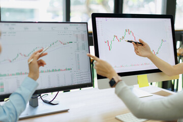 Financial professionals collaborating on stock market analysis, studying trading charts and data on...