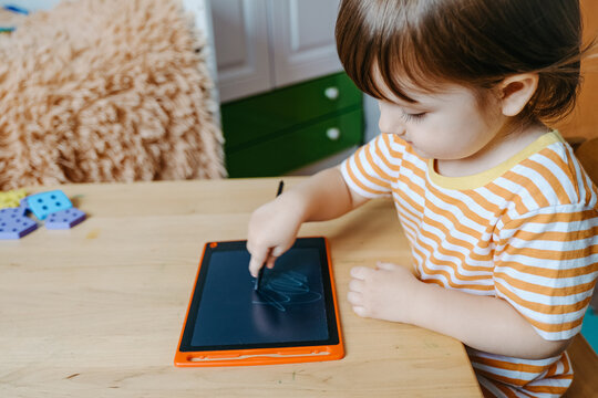 Cute Toddler Drawing on Digital LCD Writing Tablet with Stylus at Table