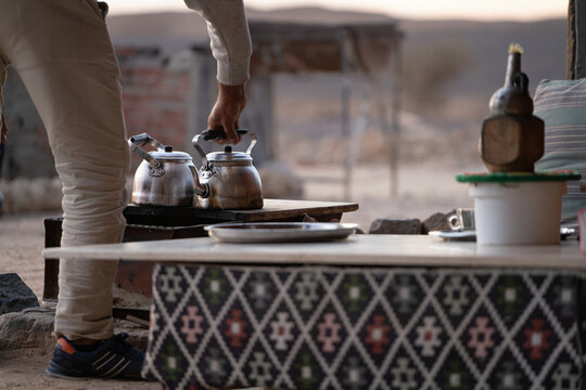 Person preparing traditional bedouin tea in desert camp