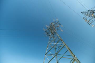 Highvoltage transmission tower stands tall against a clear blue sky in the afternoon © beholdereye