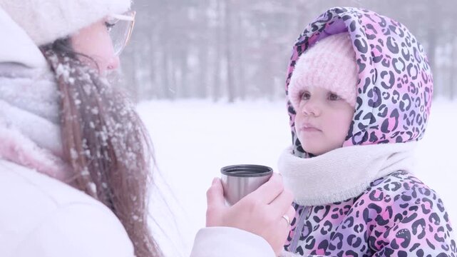 Child winter tea. Toddler drinking warm beverage outdoors. Parental care concept.