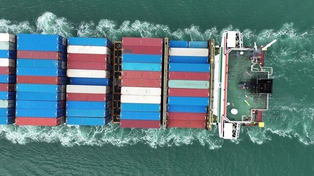 Aerial top view of cargo ship with contrail in the ocean sea ship carrying container and running from container international port smart freight shipping by ship service