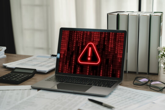 Laptop displaying red cybersecurity warning with digital code, showing malware infection, virus attack, computer security alert and online system threat in office.