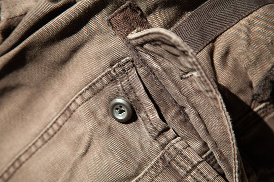 Close-up of distressed brown vintage fabric with zipper and frayed edges. Heavily worn authentic textile showing natural aging, scratches and soft material texture.	
