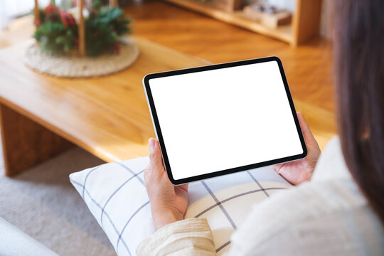 Mockup image of a woman holding tablet with blank desktop white screen at home