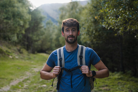 Young man hiking in forest path smiling