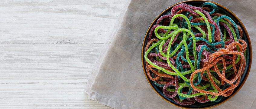 Colorful Spaghetti Jelly Candies Sprinkled with Sugar in a Bowl, top view. Copy space.