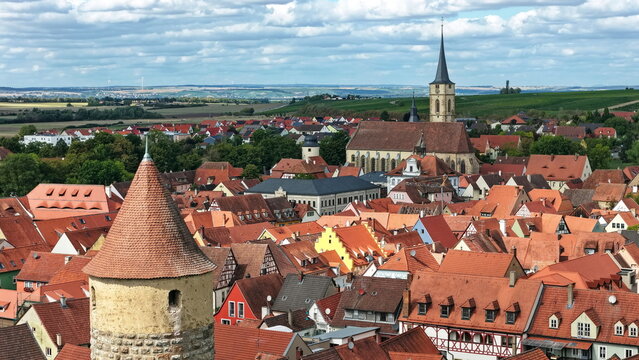 Malerische Aussicht &uuml;ber die roten D&auml;cher der historischen Altstadt von Iphofen mit einem alten Wehrturm im Vordergrund und der Stadtpfarrkirche im Hintergrund.