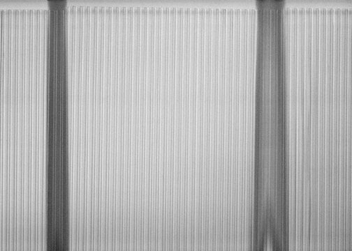 Vertical ribbed translucent glass architectural panel  scan featuring linear textures and parallel structural lines 