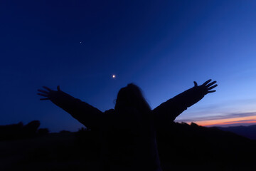 Silhouette of a person in nature observing night sky, Moon, stars and planets from a remote location. © astrosystem