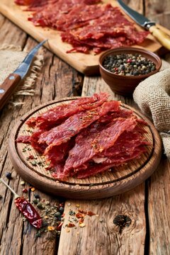 Spicy beef jerky slices on a rustic wooden board