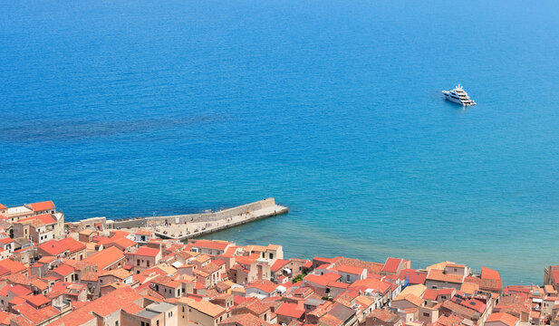 Aerial view of a coastal town with terracotta roofs and a luxury yacht in the blue sea water cruise travel vacation concept