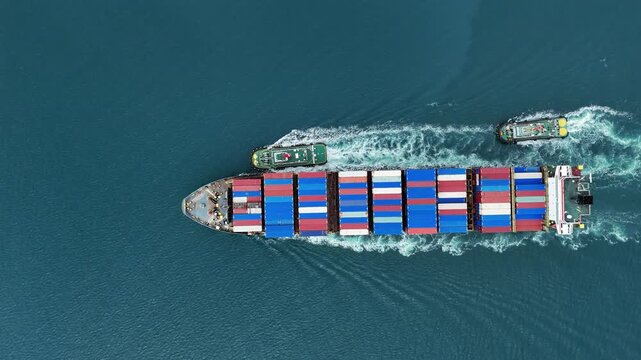 container ship fully loaded with colorful cargo being assisted by a tugboat navigating through the blue ocean. Global maritime logistics and international shipping trade concept