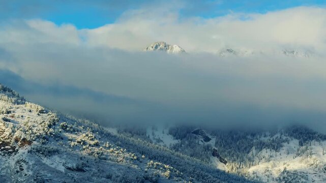 4K Landscape shot of clouds covering the snowy Himalayan mountain peaks during the winter season after a winter storm at Manali in Himachal Pradesh, India. Scenic winter wonderland background.
