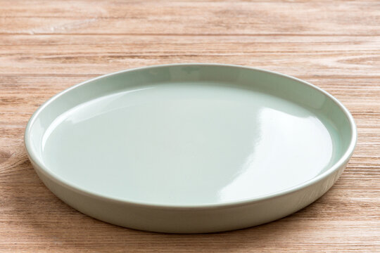 Perspective view of empty blue plate on wooden background. Empty space for your design