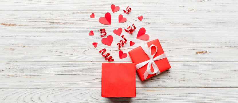 Happy valentines day opened heart shape gift box with small hearts, on colored background, valentines day card - top view concept