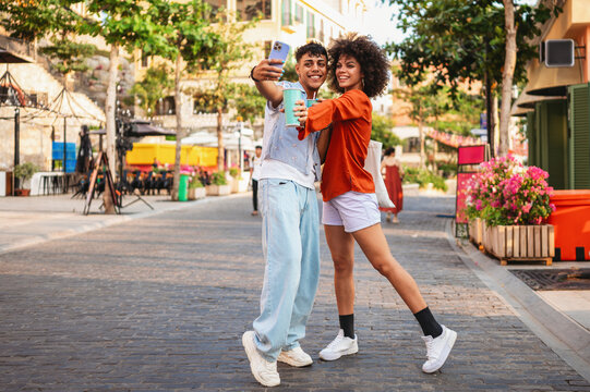 Young people capturing the vibrant urban tropical vibe, happily taking a selfie on a colorful street
