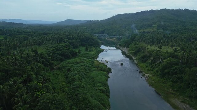 Drone footage over agricultural fields near Sipocot, Camarines Sur at dawn, showing the bridge toward Yunice Farm, rural farmland and the winding Libmanan River through the cloudy Bicol countryside.